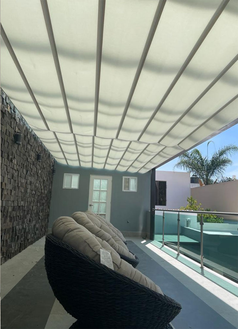 Toldo moderno sobre terraza decorada con muros tipo piedra y pisos grises, excelente opción para complementar persianas y pisos.